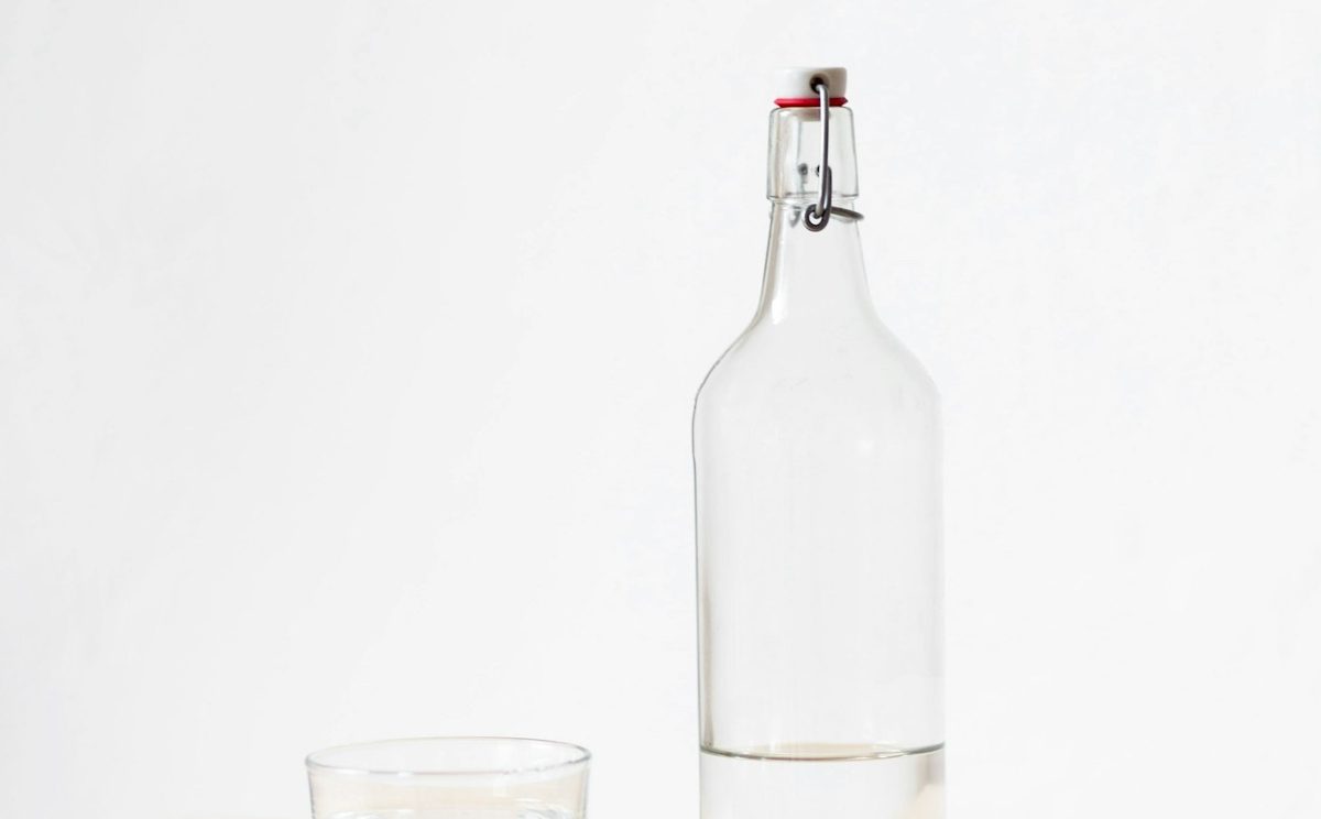 Glass bottle and tumbler of water on a bright table